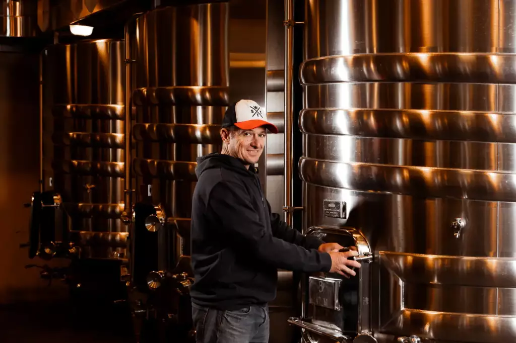 Ouvrier de chai de Laurent Giraud devant les cuves inox lors des travaux de chai en Gironde