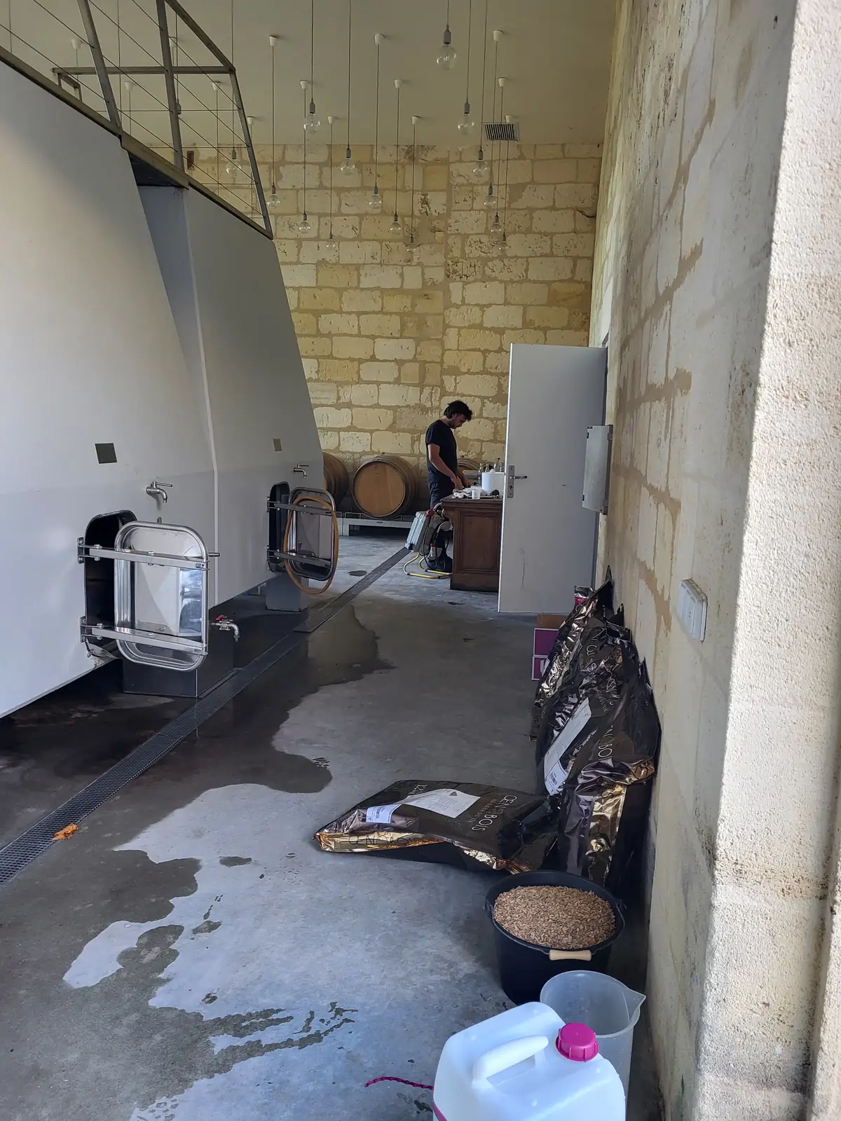 Chai de vinification en période de vendanges — Laurent Giraud, Gironde Chai de vinification en pierre avec cuves blanches à portes inox et produits œnologiques préparés pour les vendanges