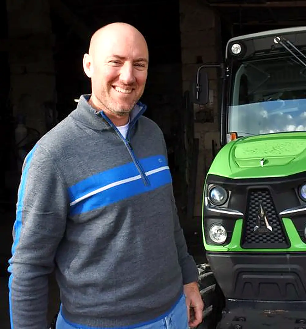 Laurent Giraud, dirigeant de Laurent Giraud Prestations Viticoles, souriant devant un tracteur vigneron